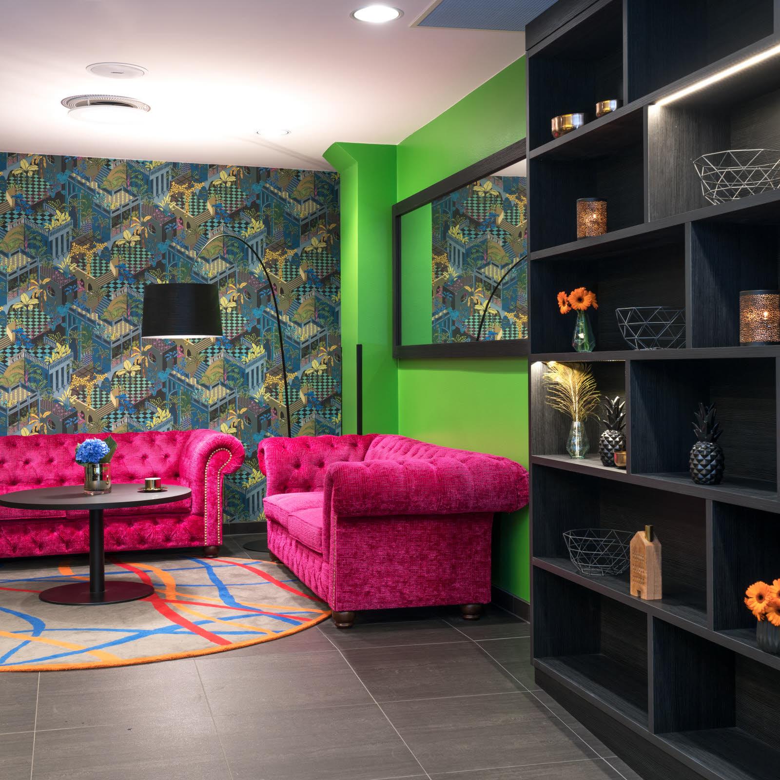 Two pink sofas in front of an apple green wall and a wallpaper wall. Thon Hotel Terminus in Oslo. Photo.