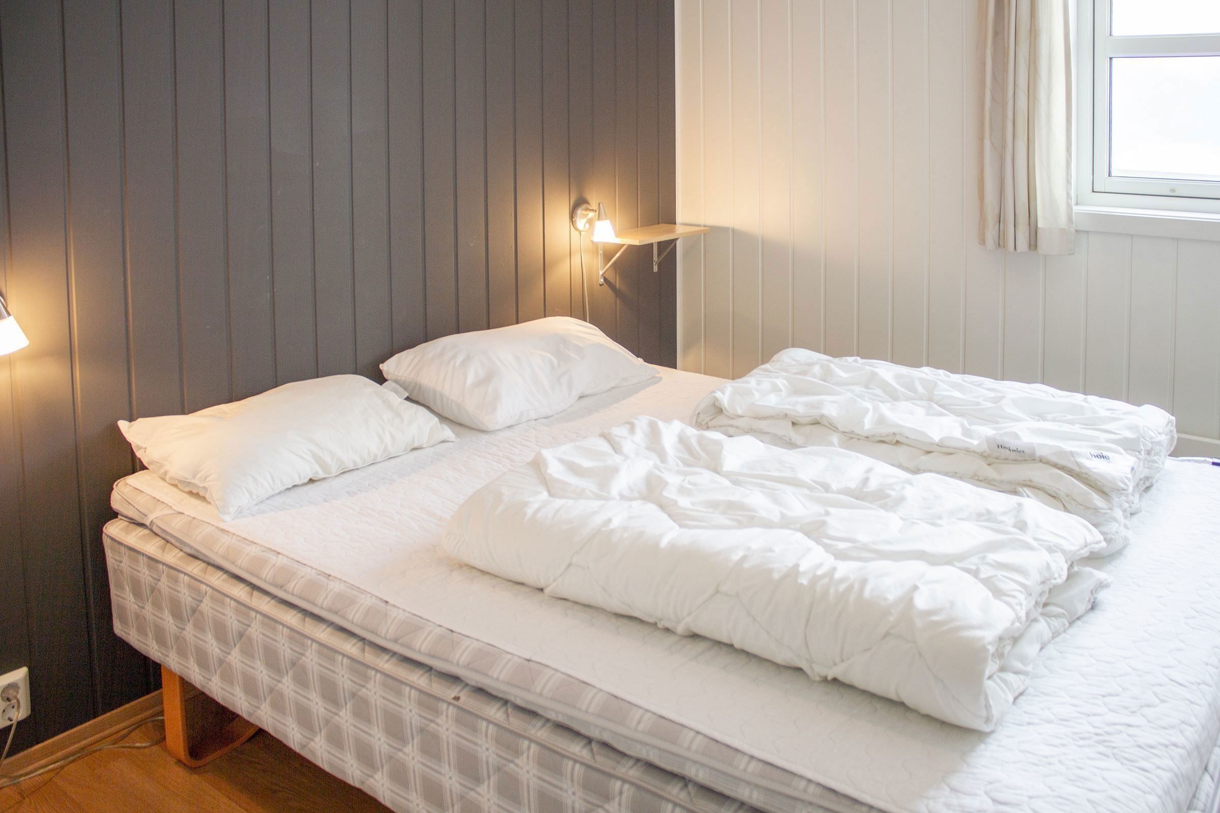 A bed with white sheets and pillows.