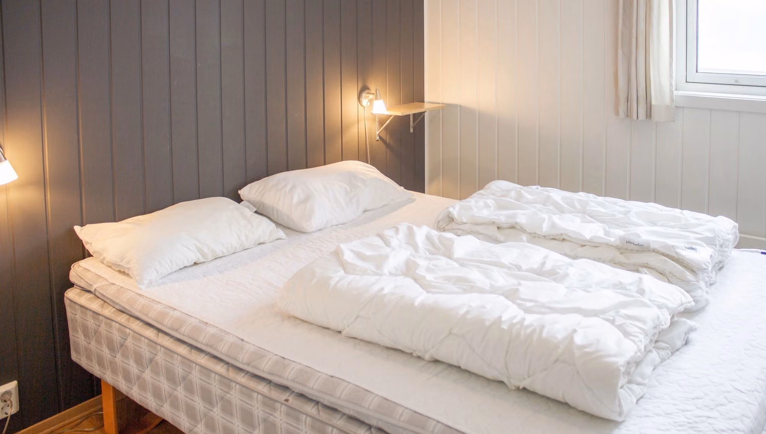 A bed with white sheets and pillows.
