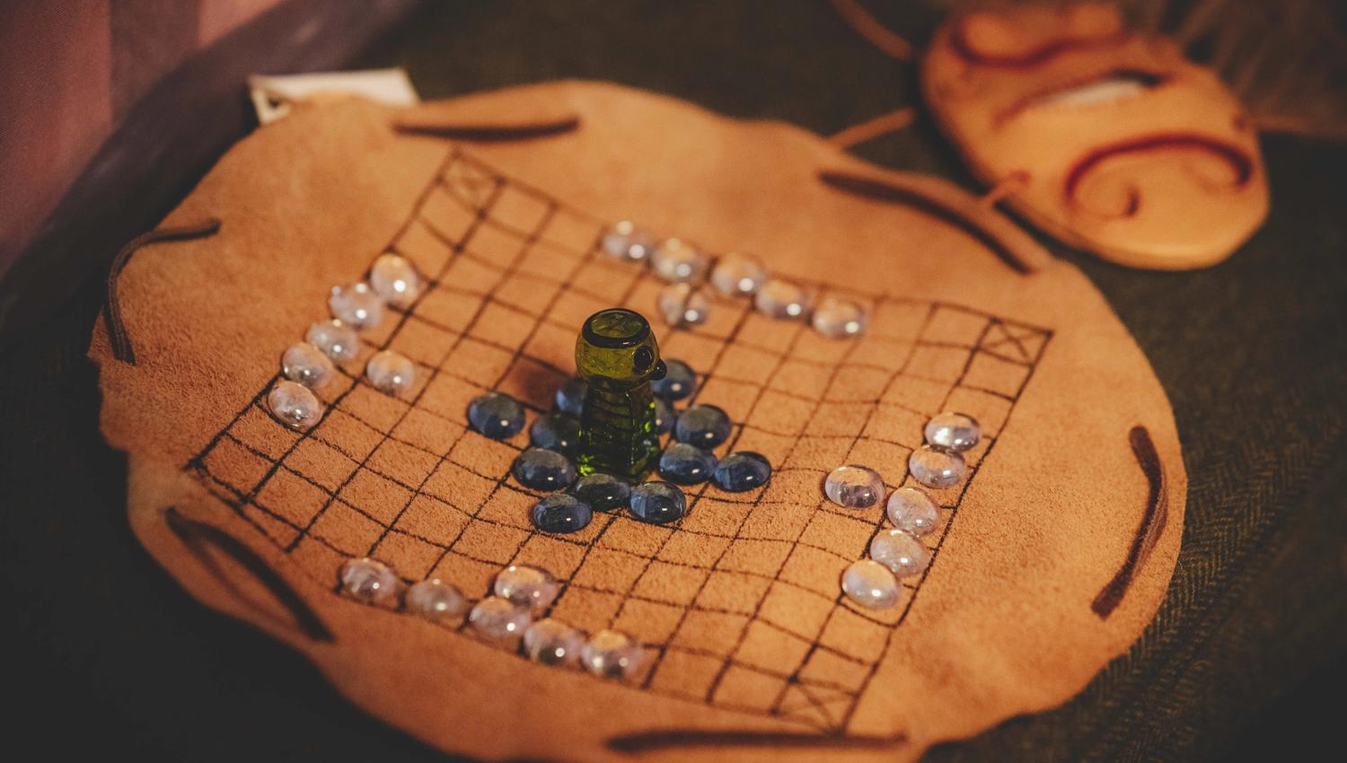 Ein Wikinger-Brettspiel, bestehend aus einem Lederstoff als Spielbrett und marmorähnlichen Steinen als Spielfiguren.