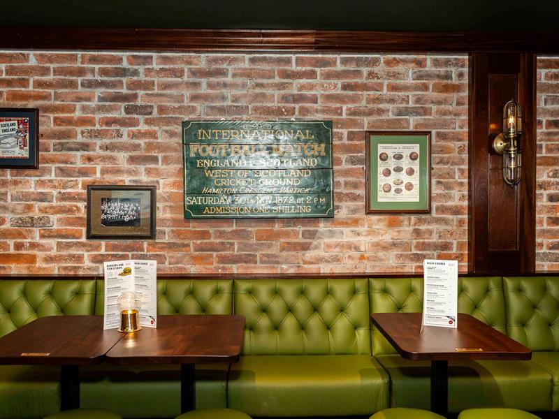 Green seating section, brown wooden tables, and a brick wall in the background