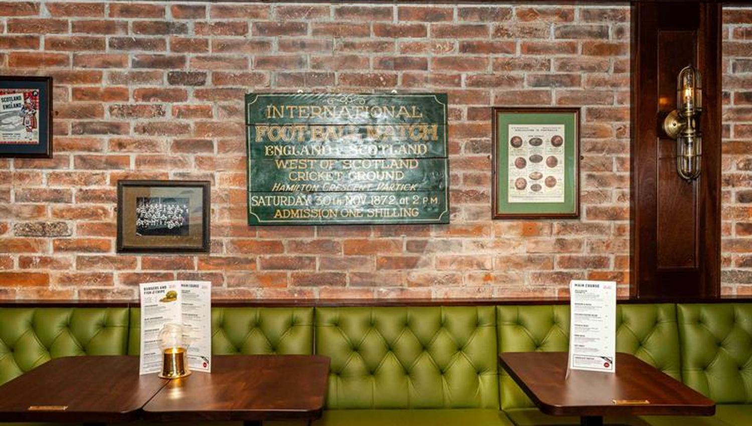 Green seating section, brown wooden tables, and a brick wall in the background
