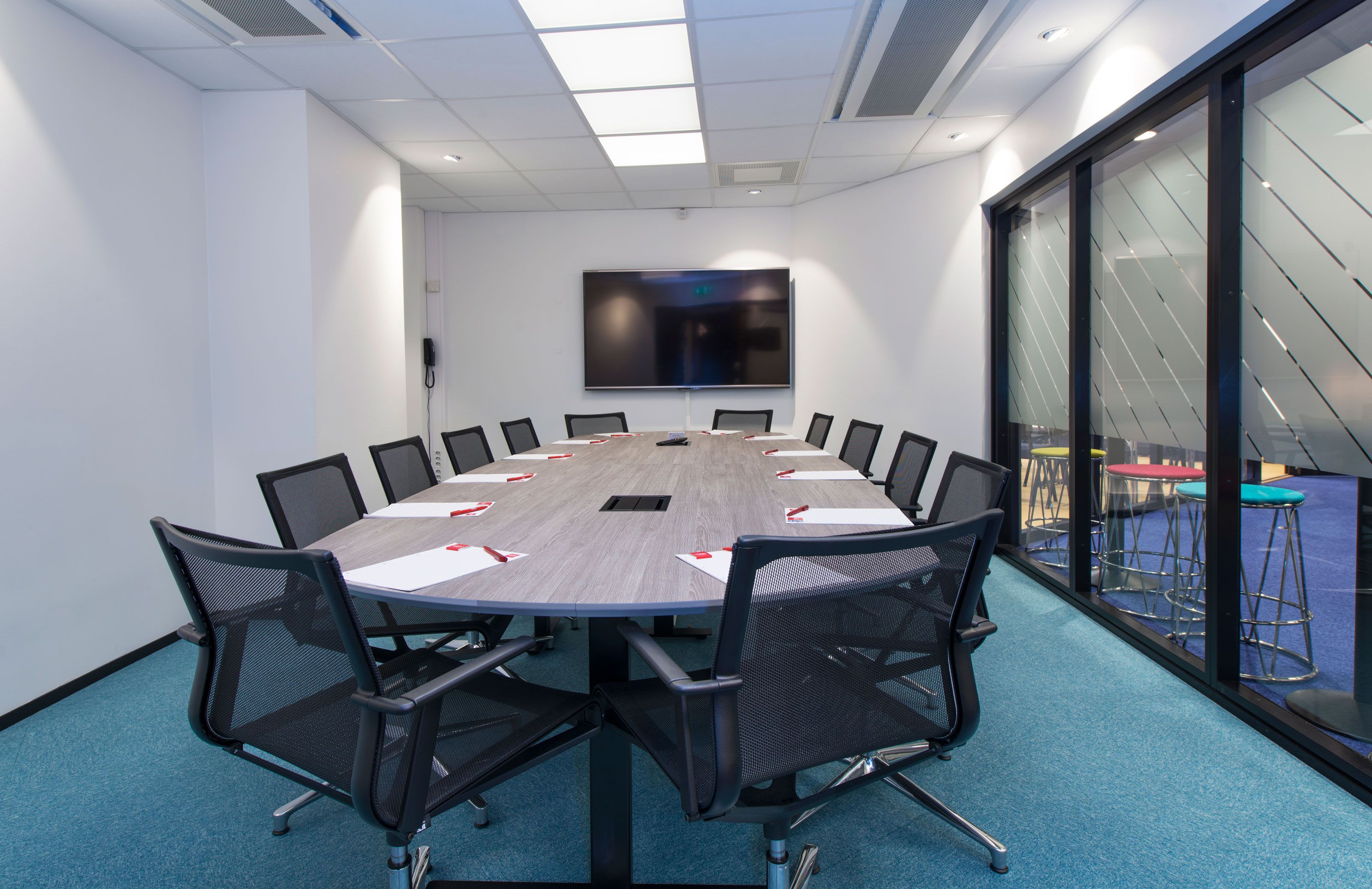 conference room with large conference table, office chairs and TV screen
