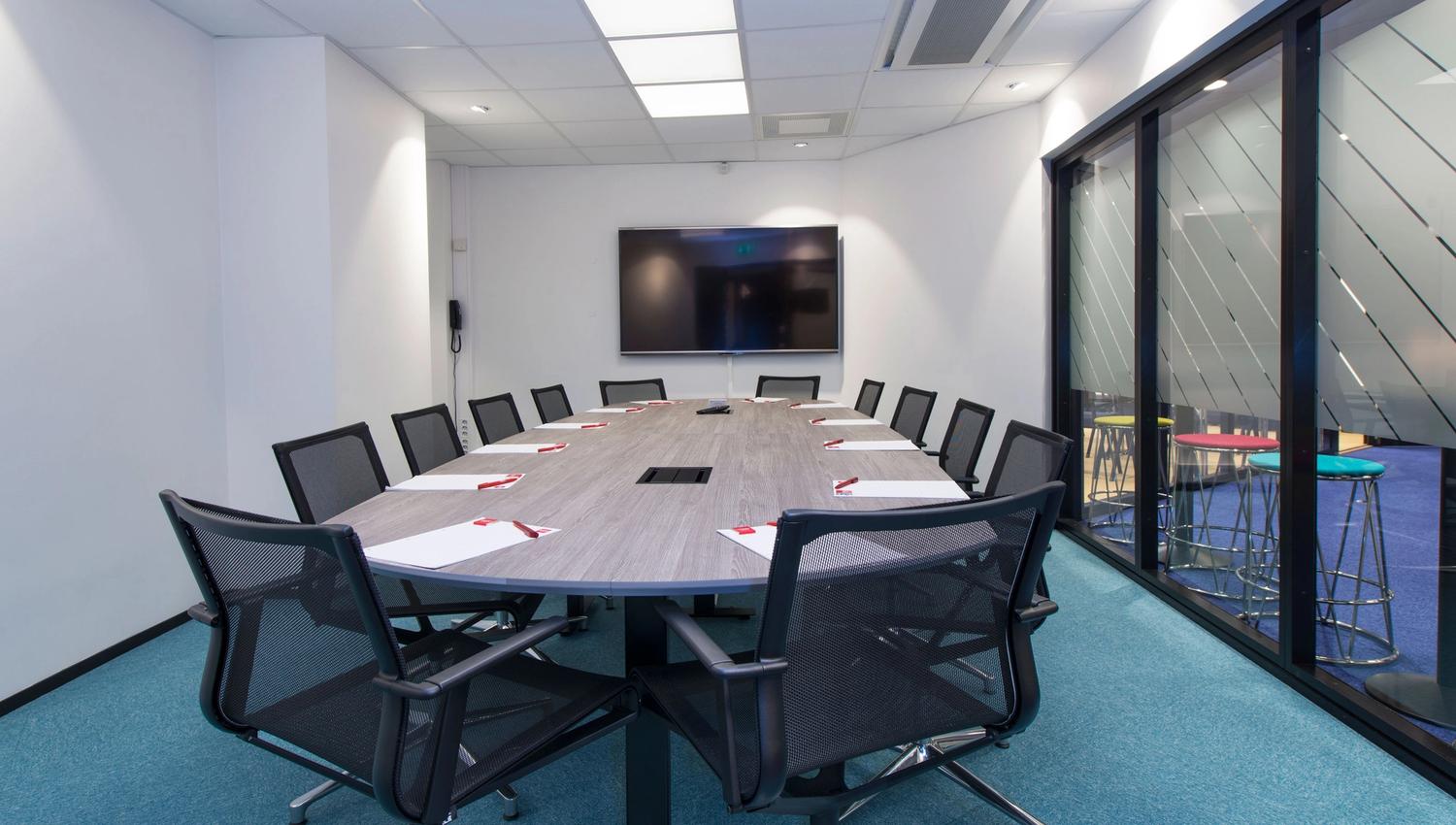 conference room with large conference table, office chairs and TV screen