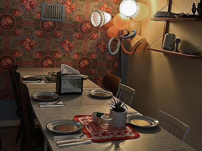 Oppdekket bord med tallerkener, glass og blomster i et kafélokale med mønstret tapet hos Nummer Ti i Horten.