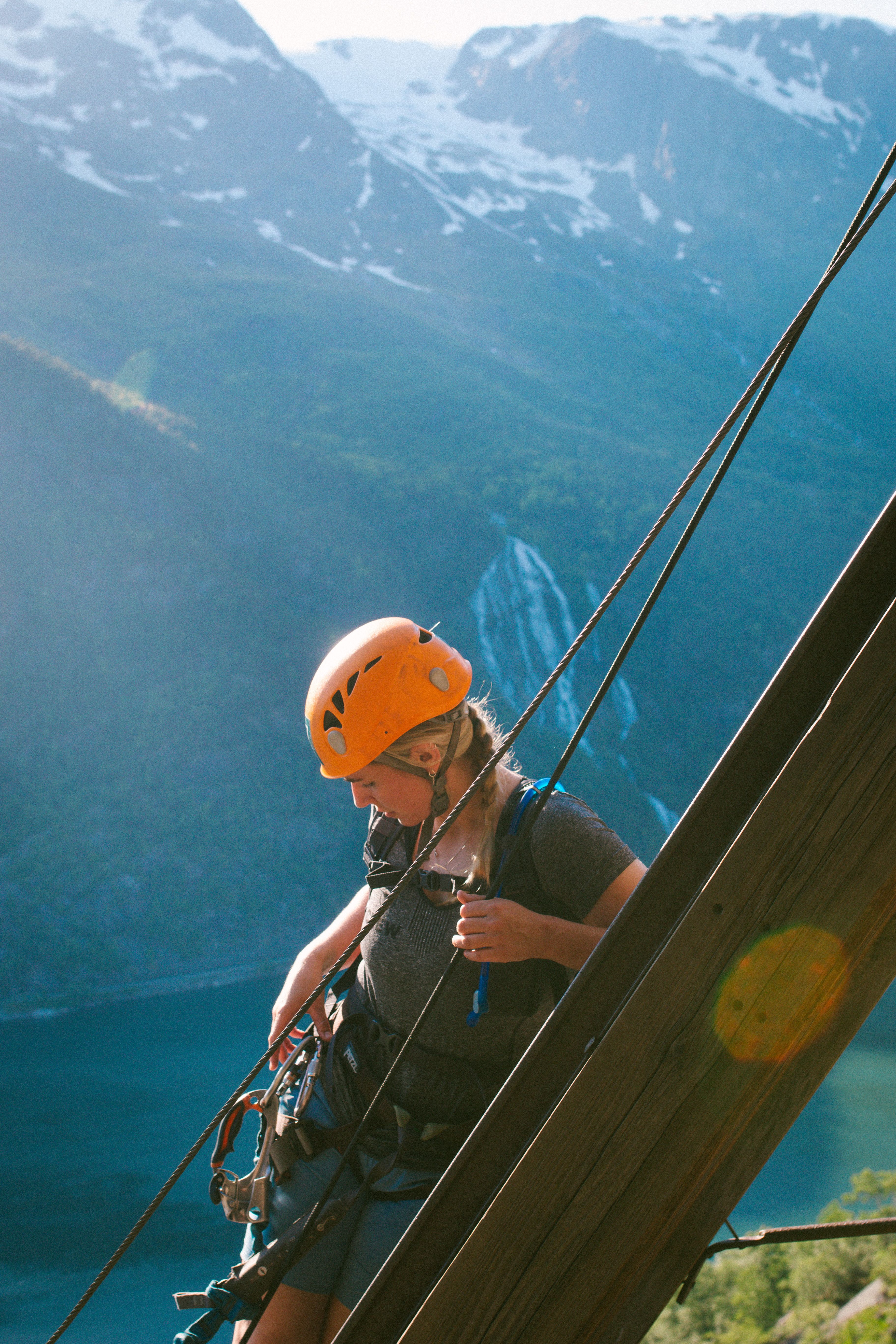 Climber secured to the steel cable with waterfall and mountains in the background.