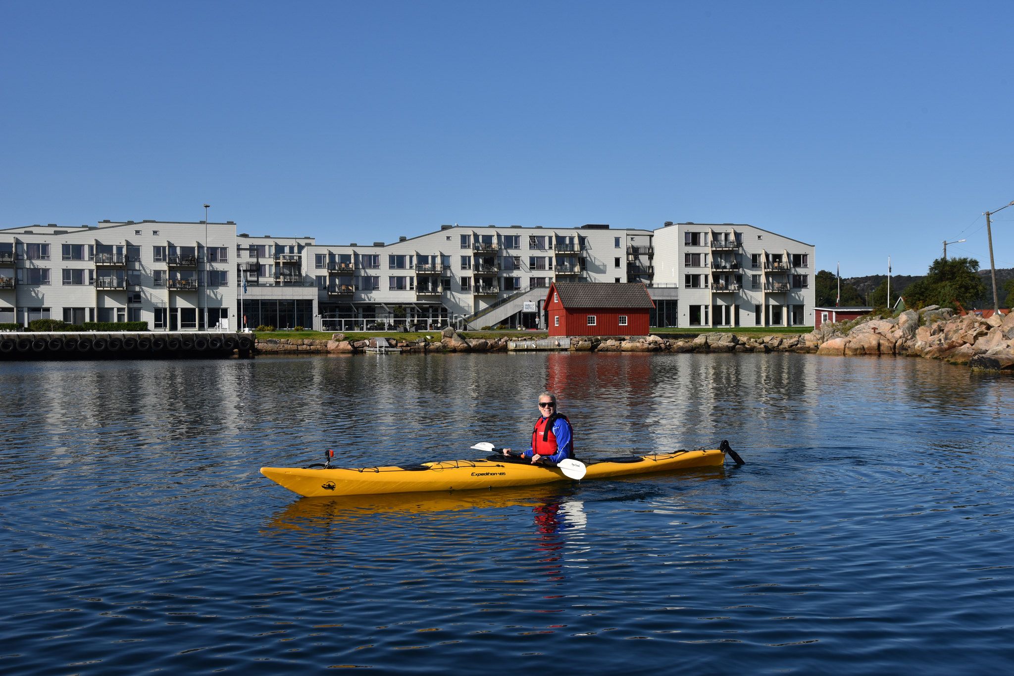 Blid kvinne i en gul kajakk utenfor Lindesnes Havhotell