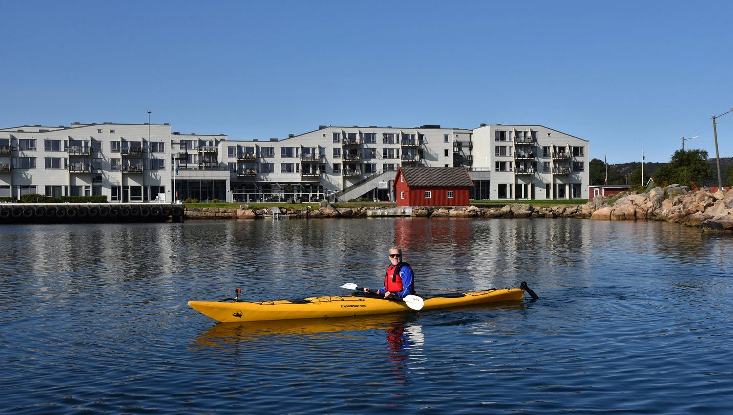Blid kvinne i en gul kajakk utenfor Lindesnes Havhotell