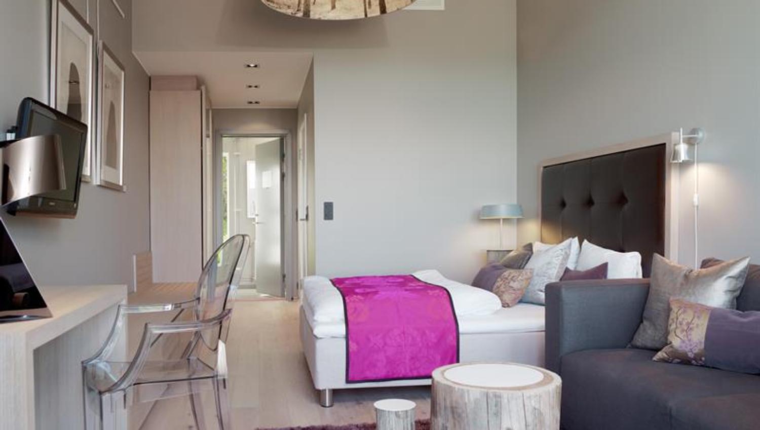 Guest room. Bed, couch and desk. Dark purple and deep pink decor. Photo.