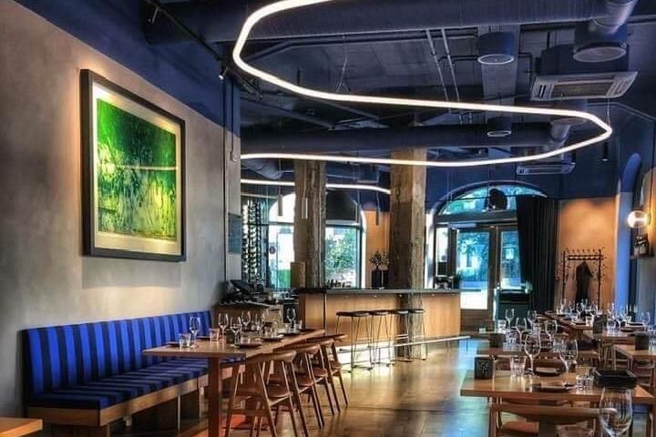 Interior with blue upholstered benches, tables set for dining and blue ceiling.
