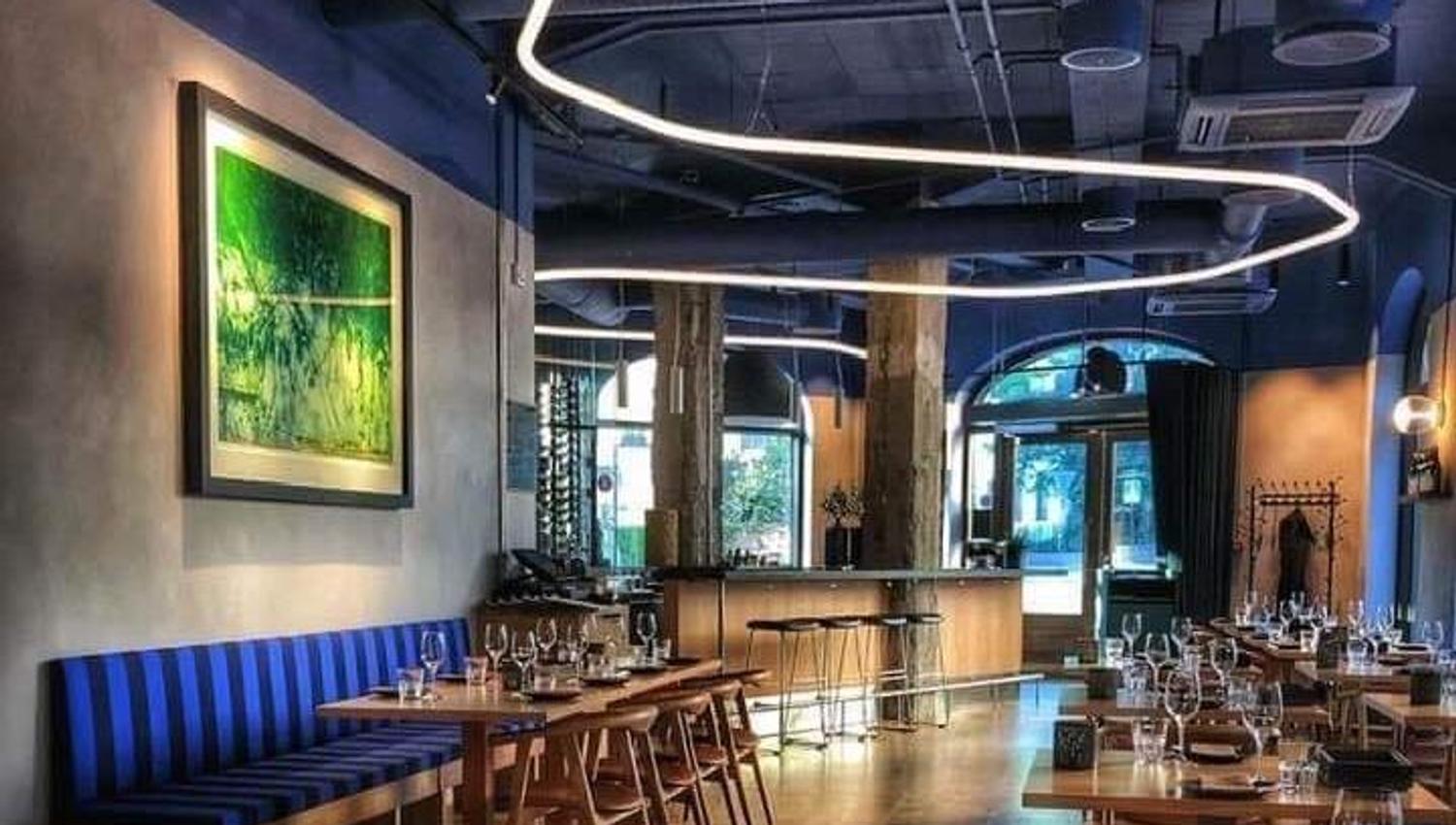 Interior with blue upholstered benches, tables set for dining and blue ceiling.