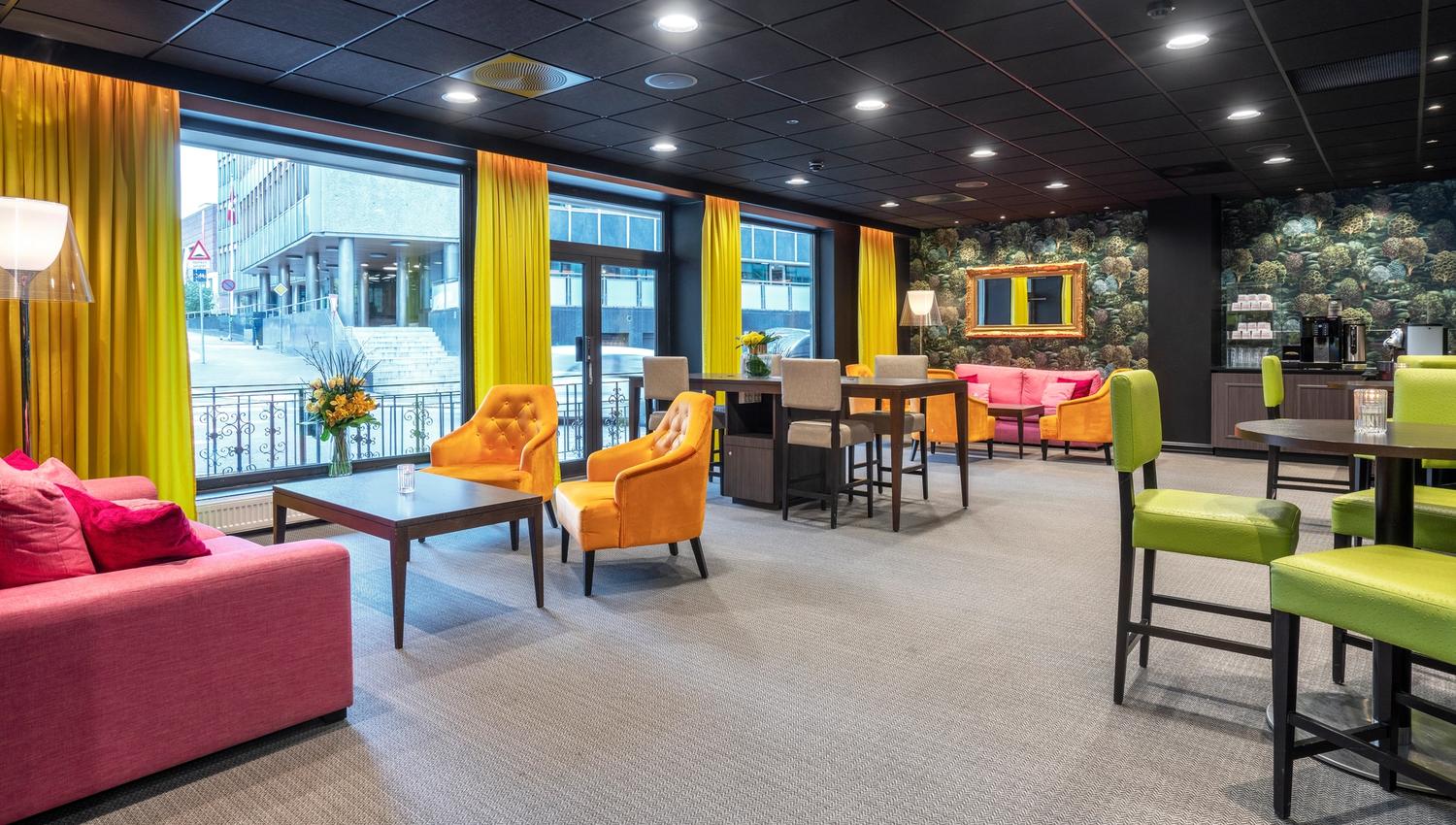 Lobby with sofas and chairs in red, green and orange. Yellow curtains. Thon Hotel Slottsparken, Oslo