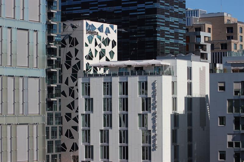 Modern hotel façade with a rooftop terrace overlooking central Oslo.
