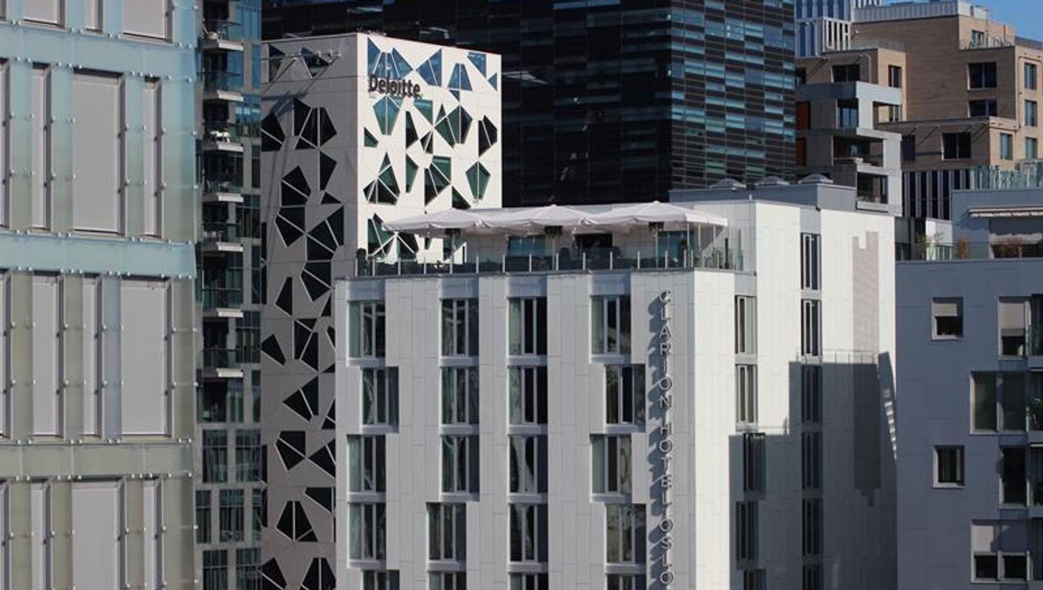 Modern hotel façade with a rooftop terrace overlooking central Oslo.
