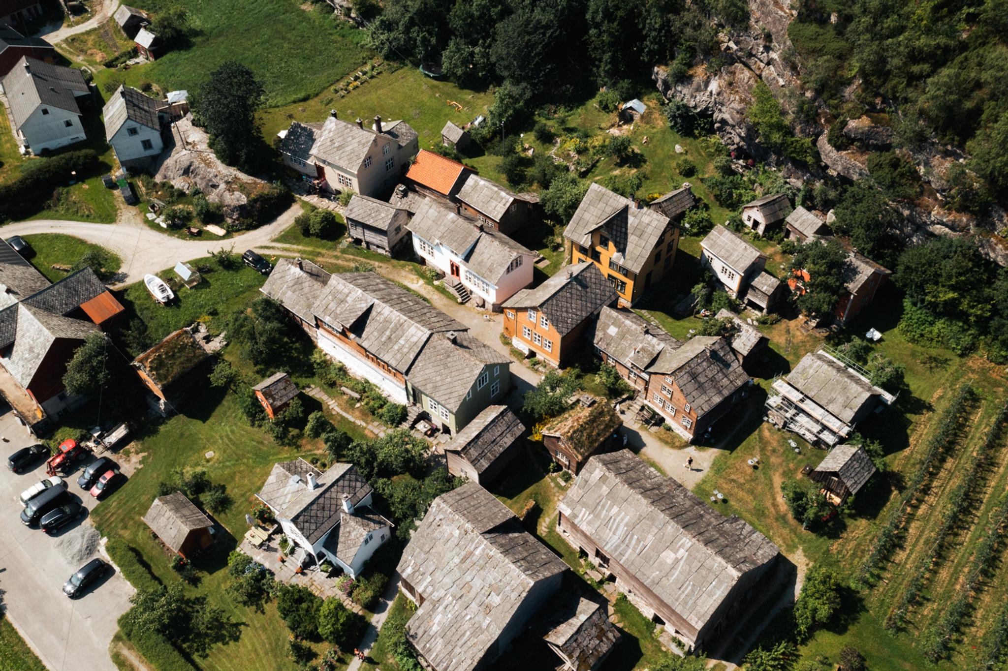 Drone photo of Agatunet with historic wooden houses clustered together, surrounded by green landscape and orchards.