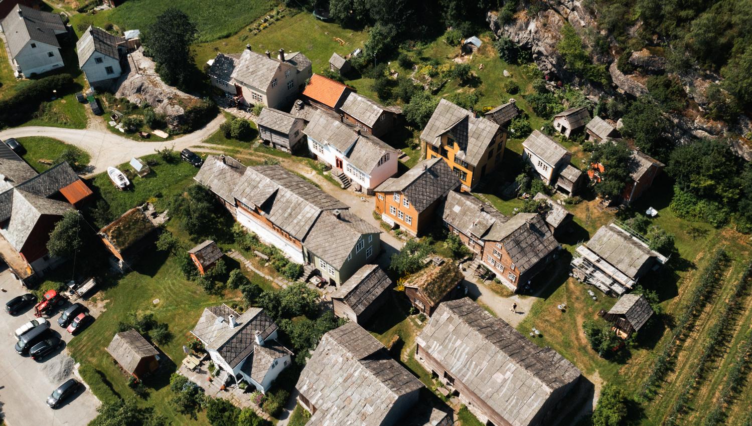 Drone photo of Agatunet with historic wooden houses clustered together, surrounded by green landscape and orchards.