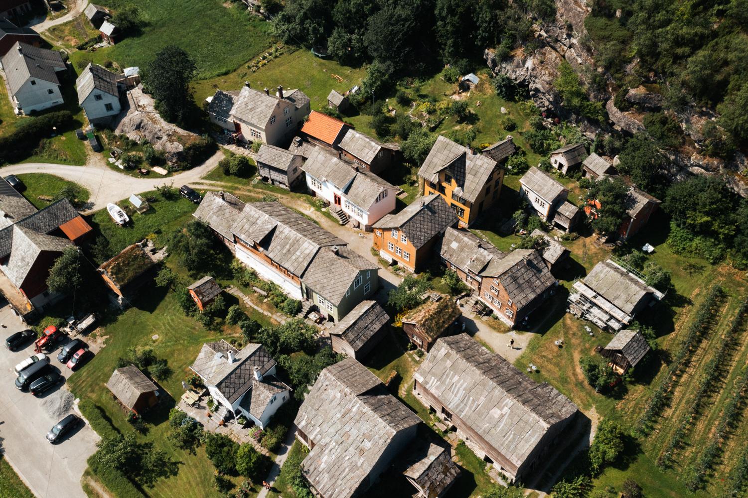 Drone photo of Agatunet with historic wooden houses clustered together, surrounded by green landscape and orchards.