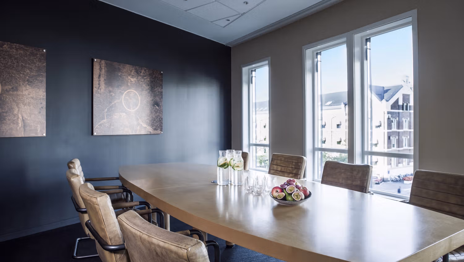 Meeting room with six chairs around the table. Apples and water pitchers on the table. Photo