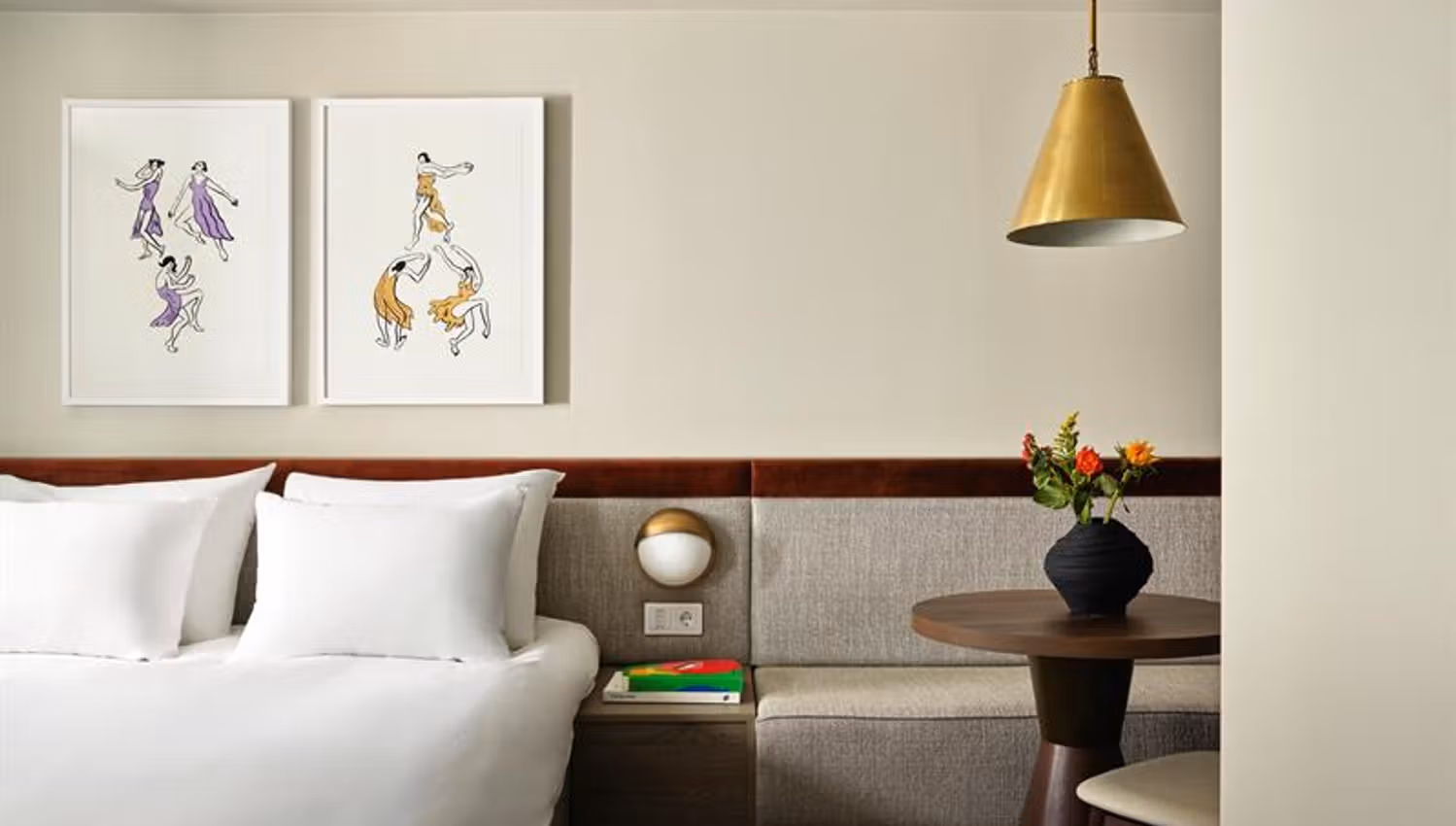 The rooms feature a double bed, integrated seating and wall-mounted lighting. The interior combines textiles, wood finishes and framed artwork.