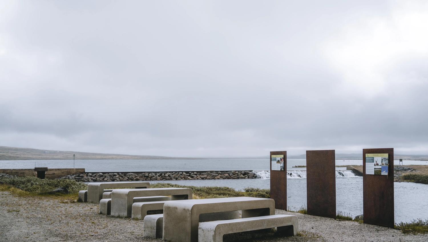 Noen betongbenker og bord med noen informasjonstavler i bakgrunnen.