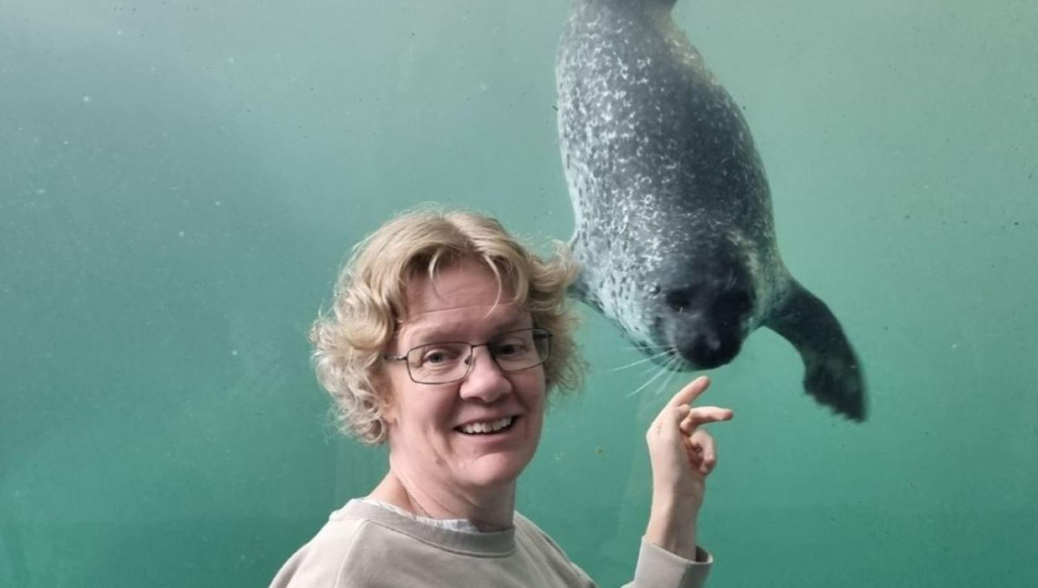 A person pointing at a seal in an aquarium