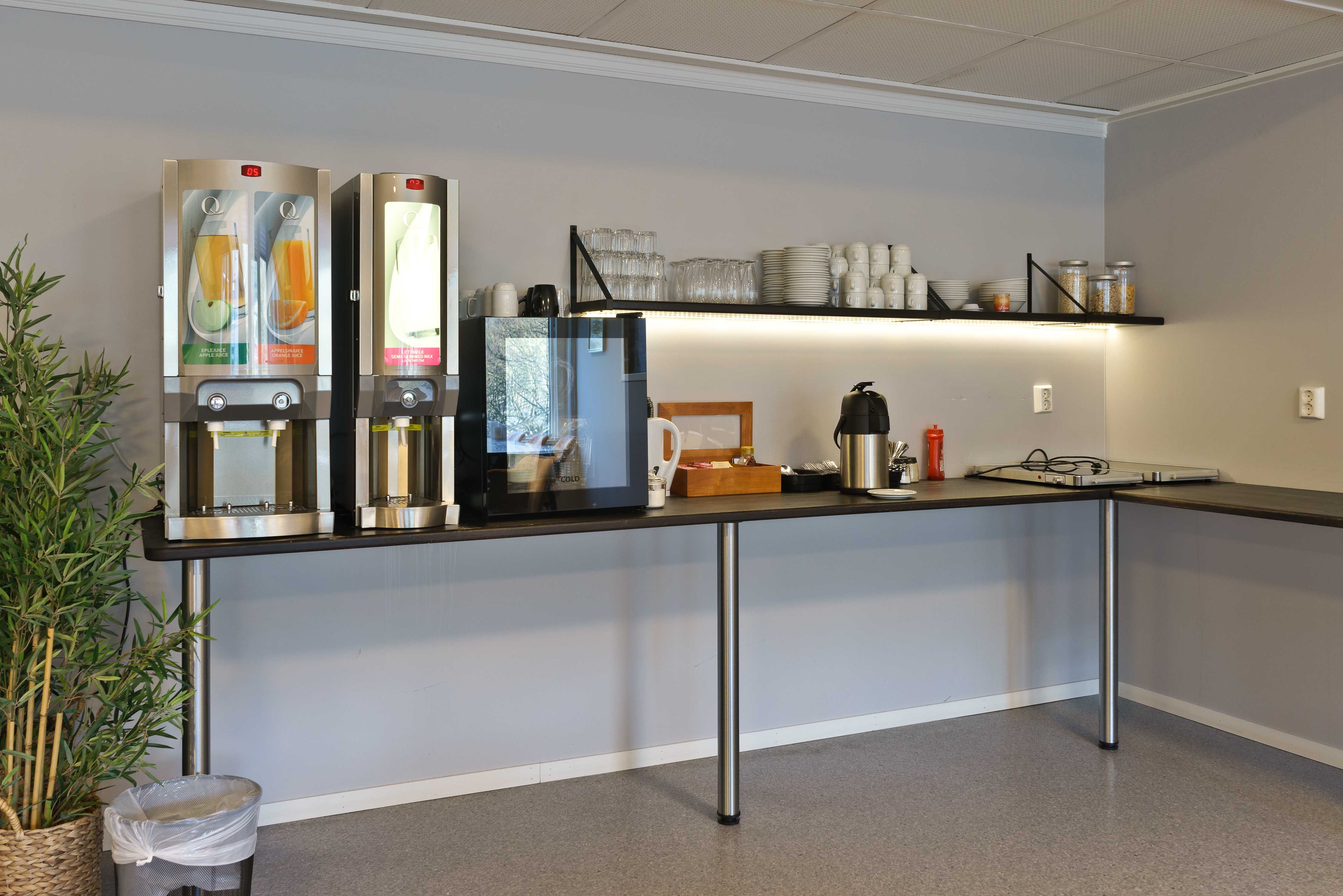 Frokostområde på Husnes Sentrum Hotell med juicemaskin, kaffi og moderne fasilitetar.