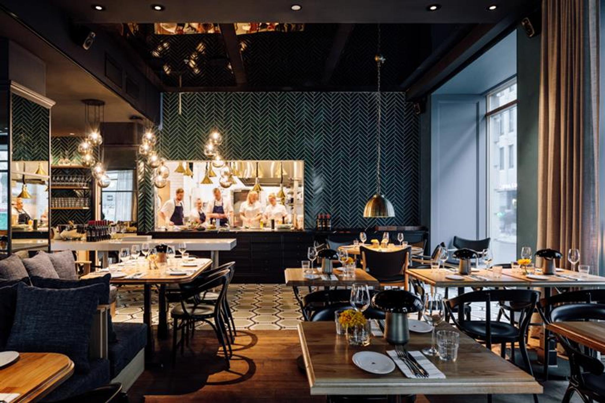 Restaurant Atlas - interior photo. Set tables with chairs, seating section, hanging ceiling lamps and the kitchen in the background.