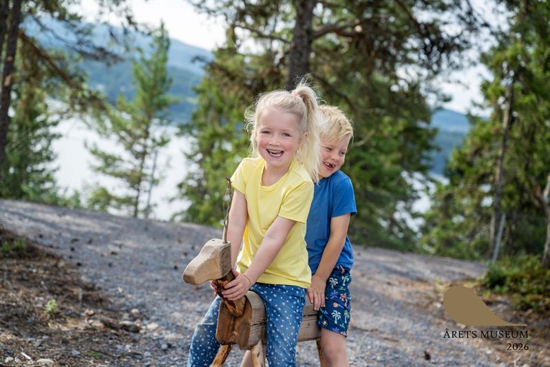 Girl and boy playing on a wooden animal sculpture
