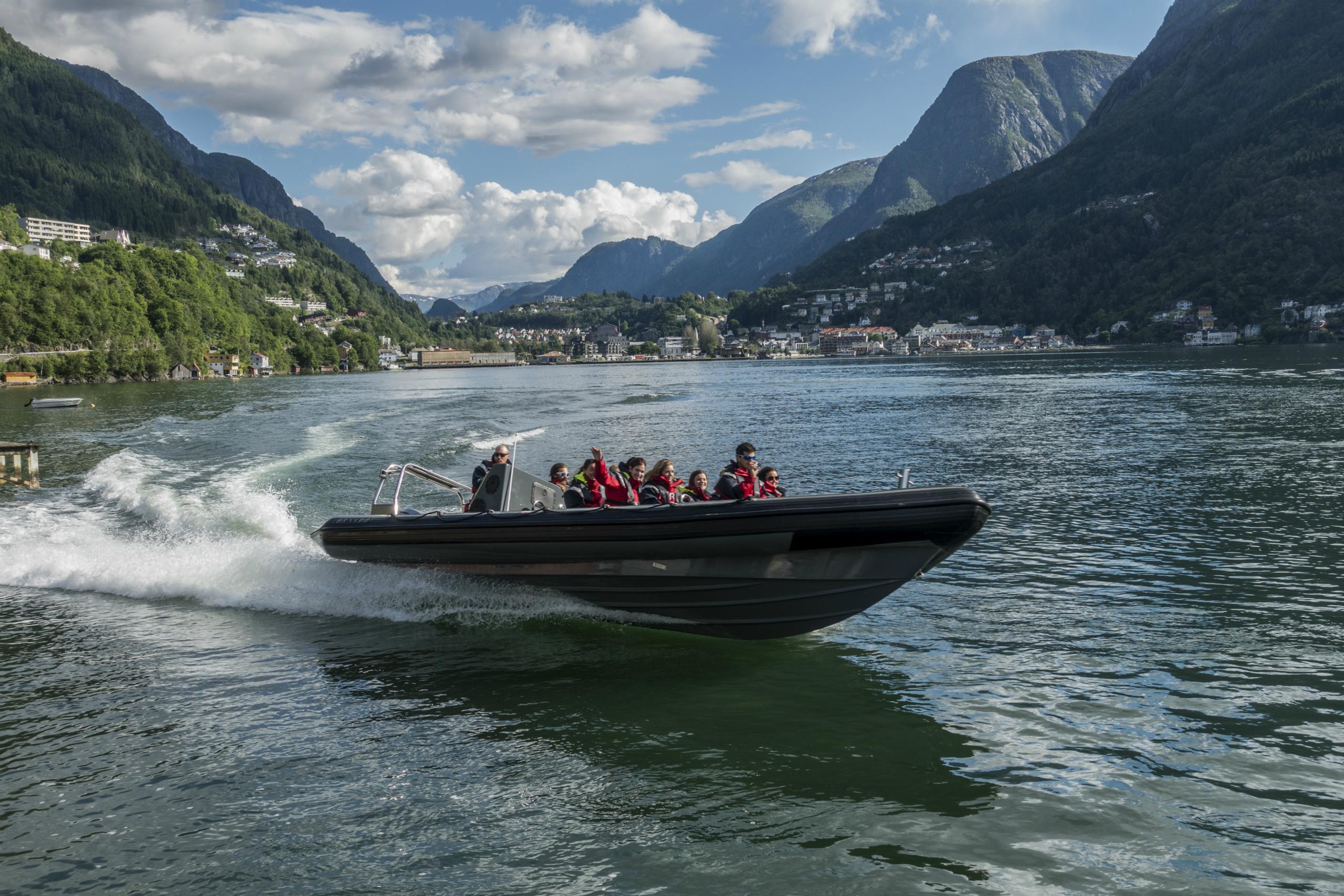 A RIB boat speeds across the Hardangerfjord, surrounded by stunning mountains.