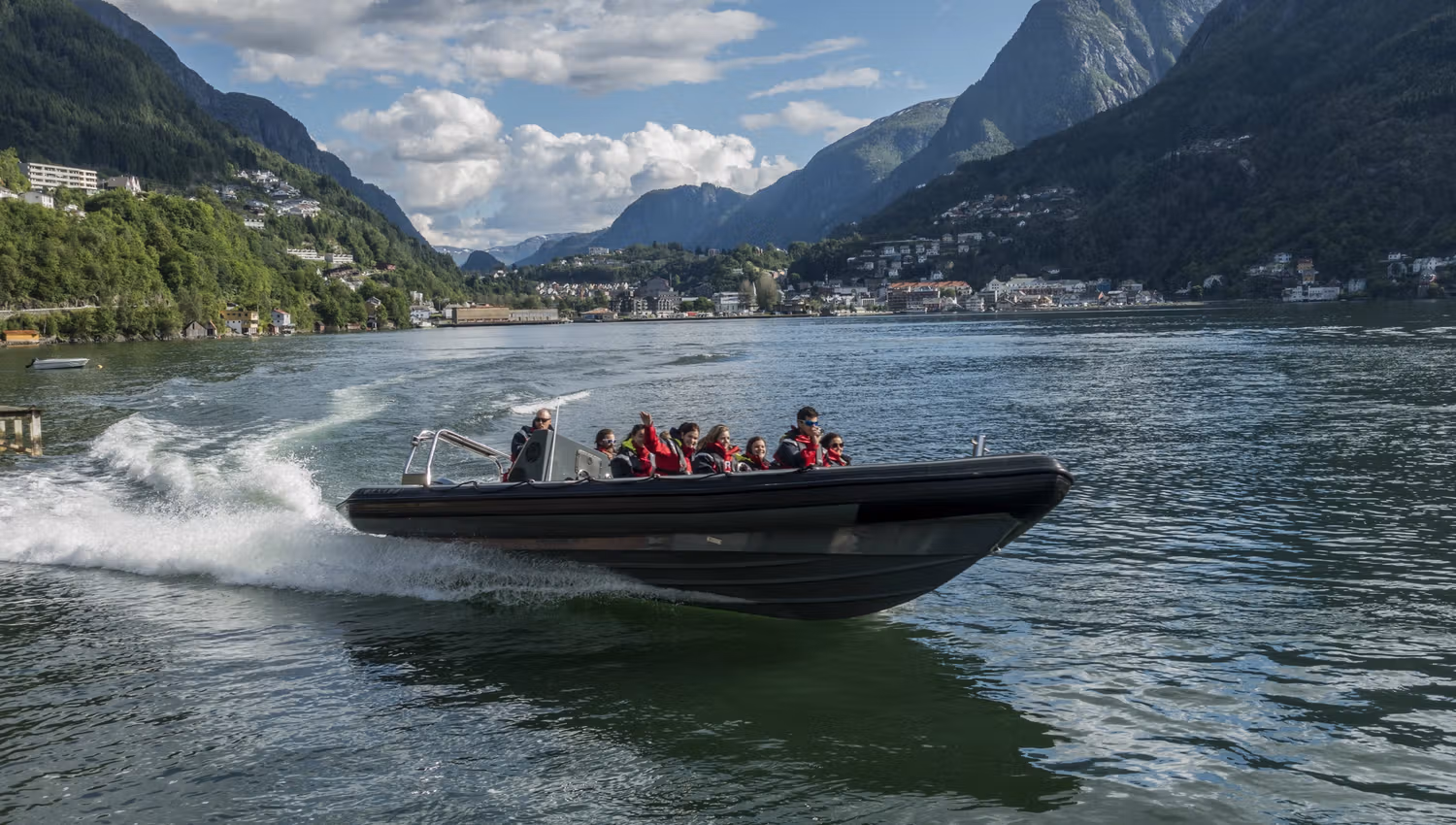 RIB-båt susar over Hardangerfjorden med spektakulære fjell i bakgrunnen.