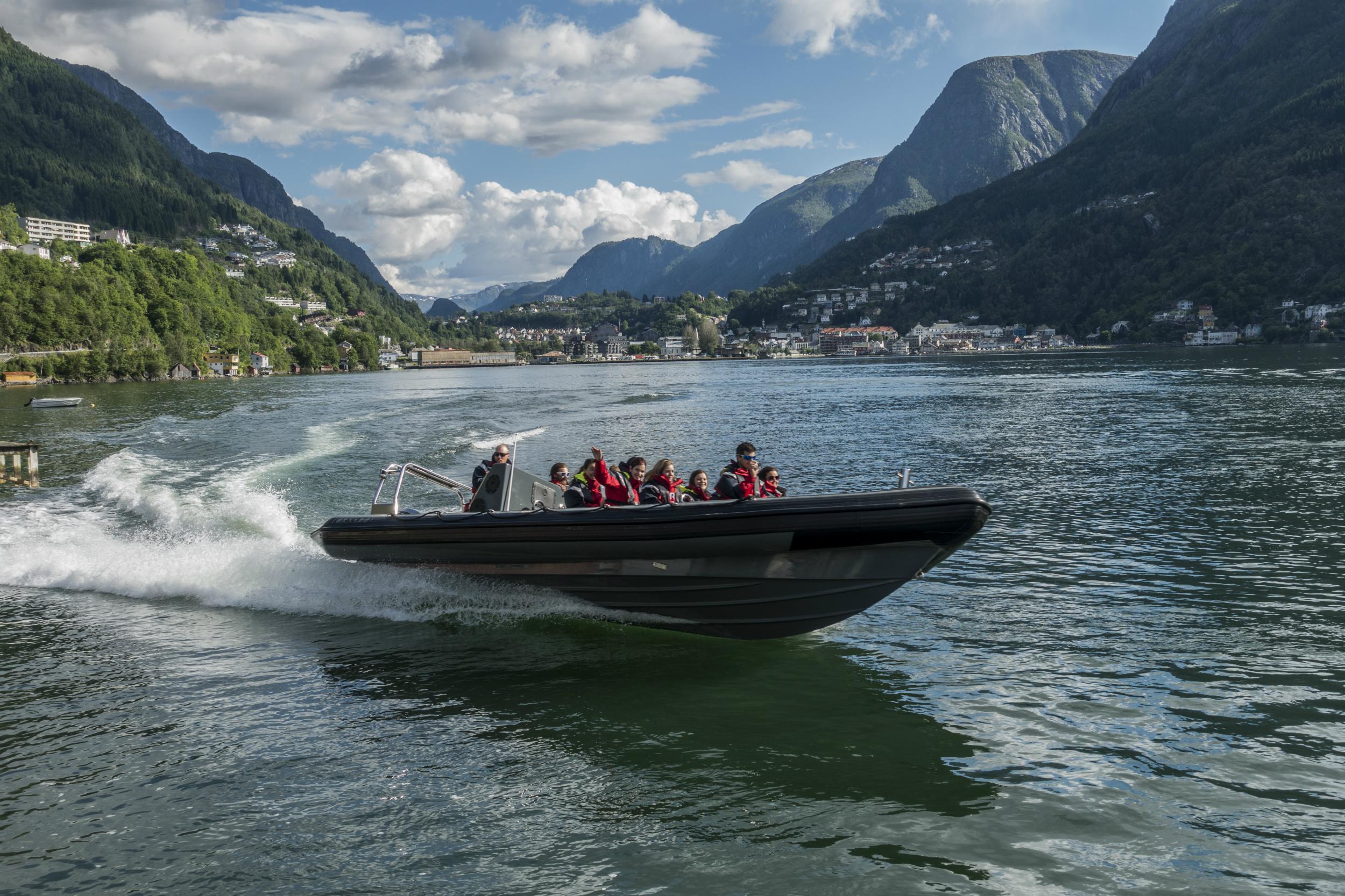 A RIB boat speeds across the Hardangerfjord, surrounded by stunning mountains.