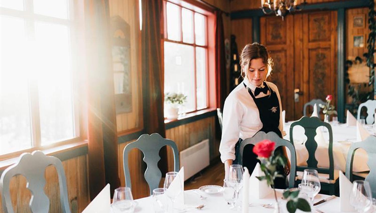 waitress sets the table at the restaurant at Tuddal Høyfjellshotell