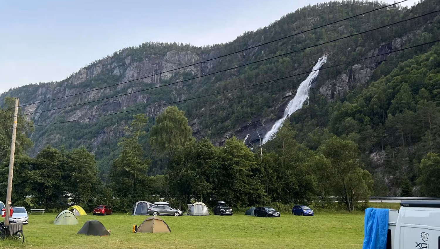 Gäste entspannen sich auf dem Hildal Camping mit Blick auf den Wasserfall im Oddatal.