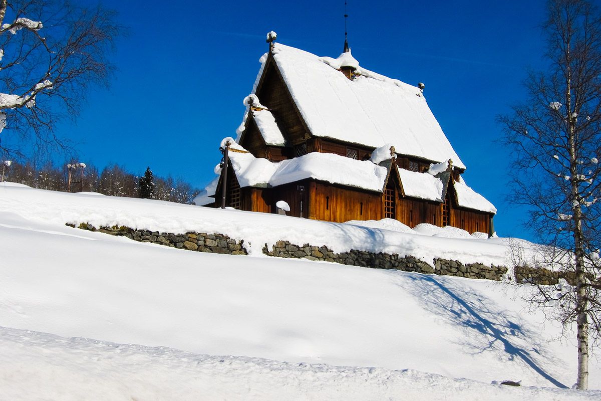 Snødekt stavkirke i Reinli en skyfri vinterdag.