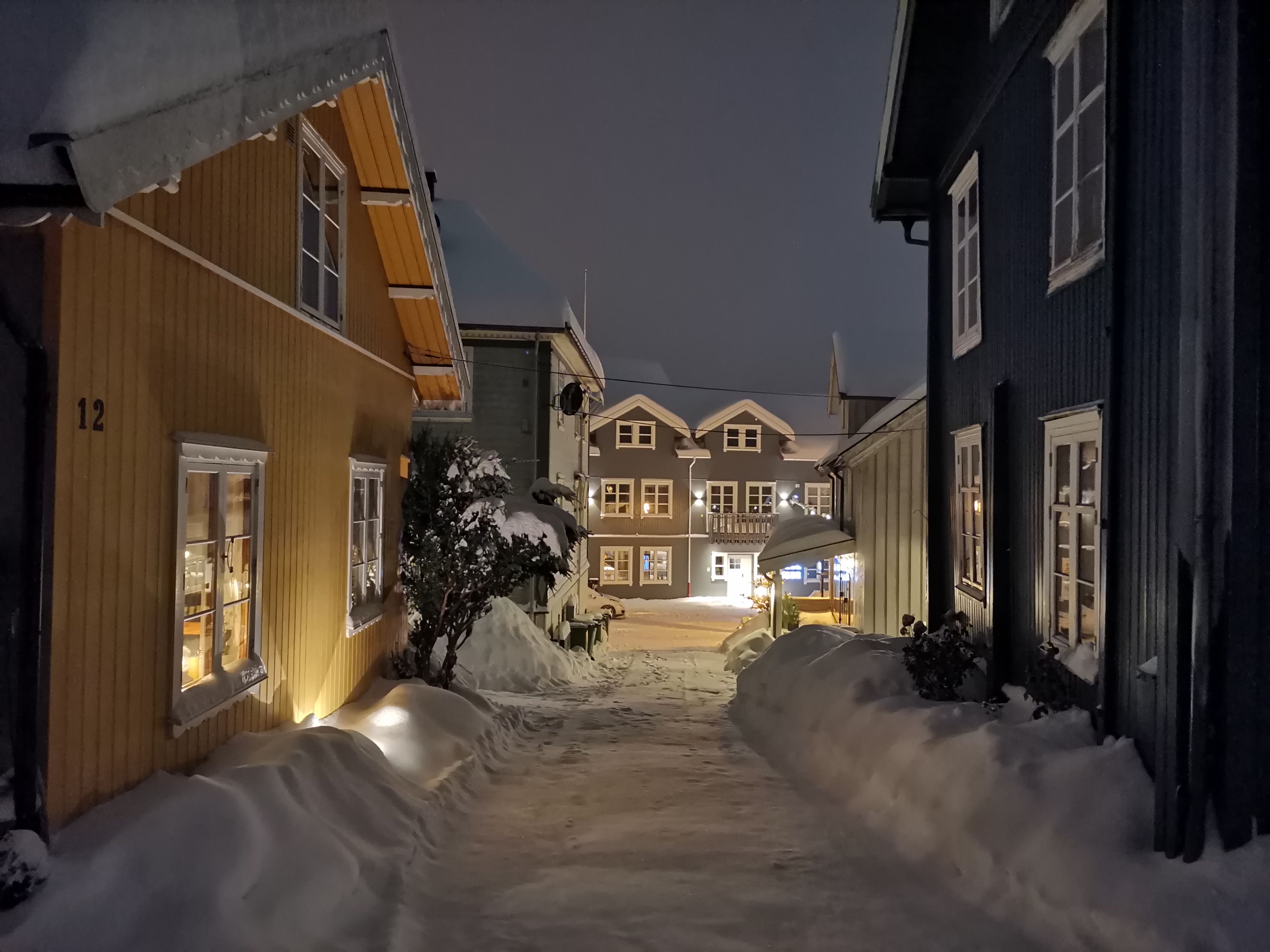 Gult hus med snø i en smal gate