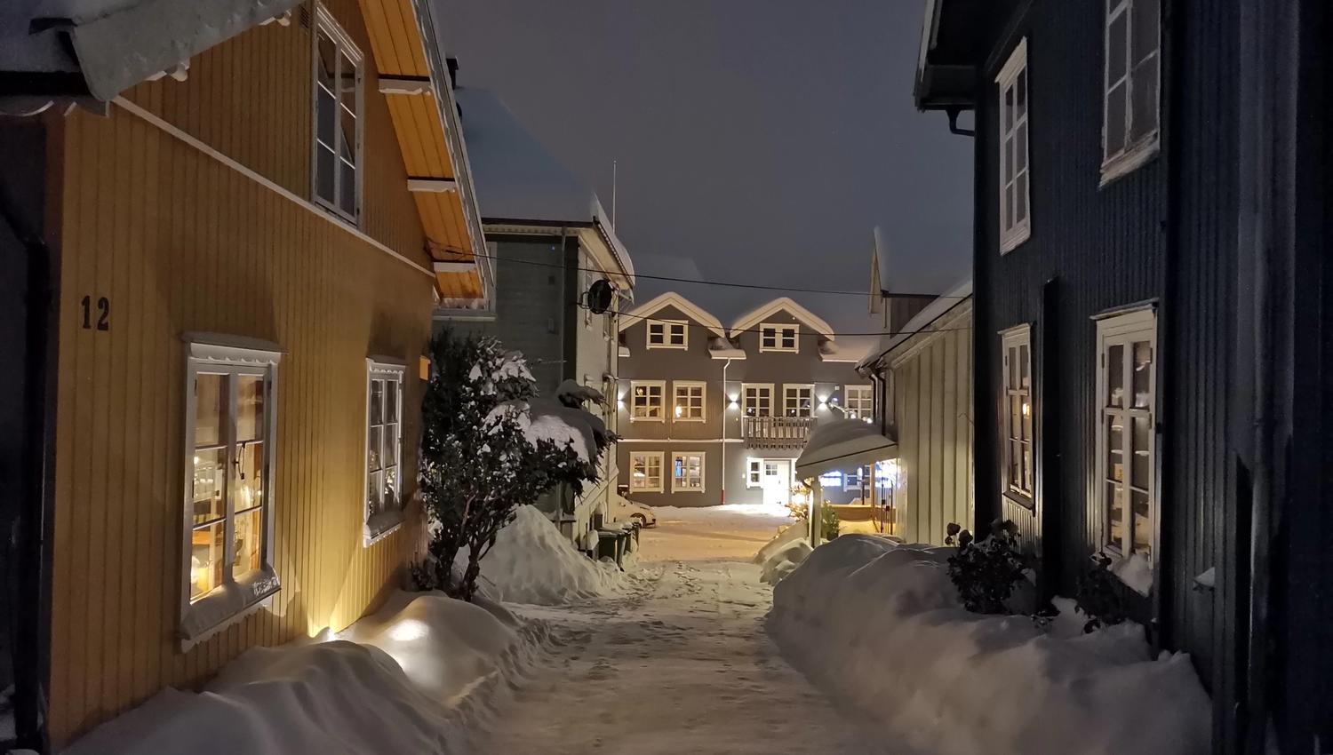 Gult hus med snø i en smal gate