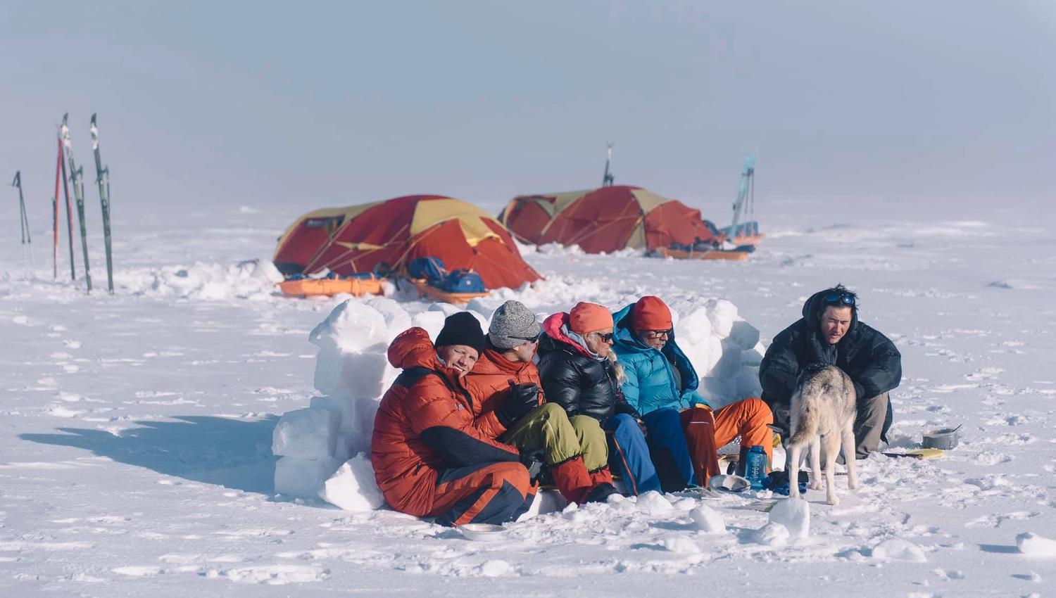 A tour group sitting huddled up together in a tent camp