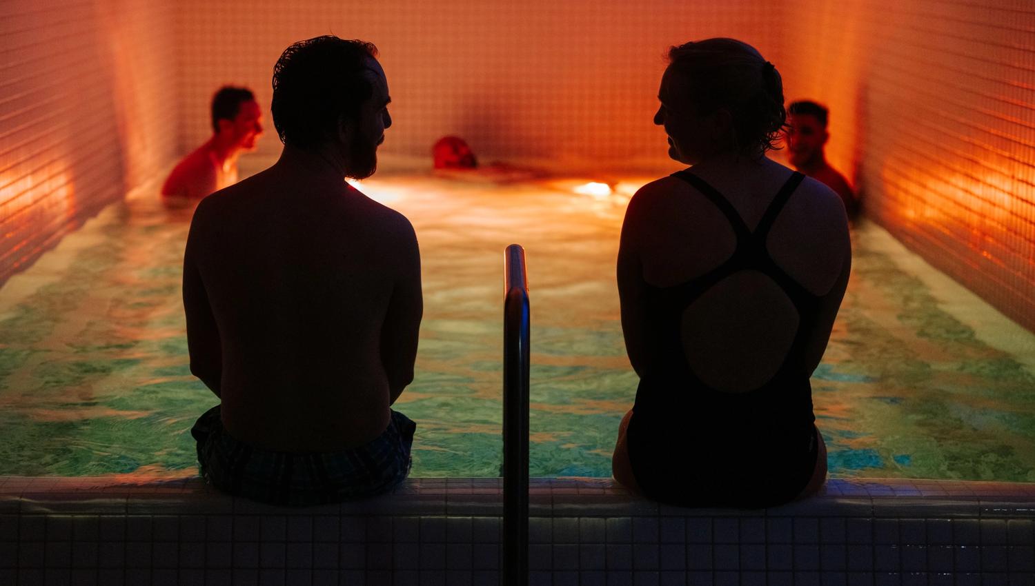 People relaxing in a small indoor pool with dim lighting