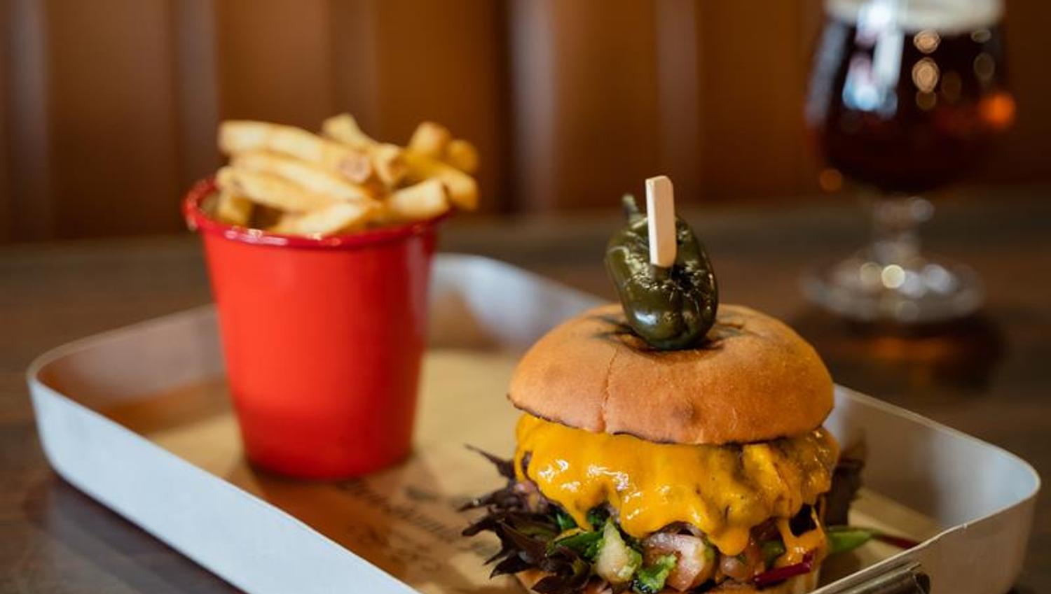 Detalj av cheeseburger, pommes frites og øl.