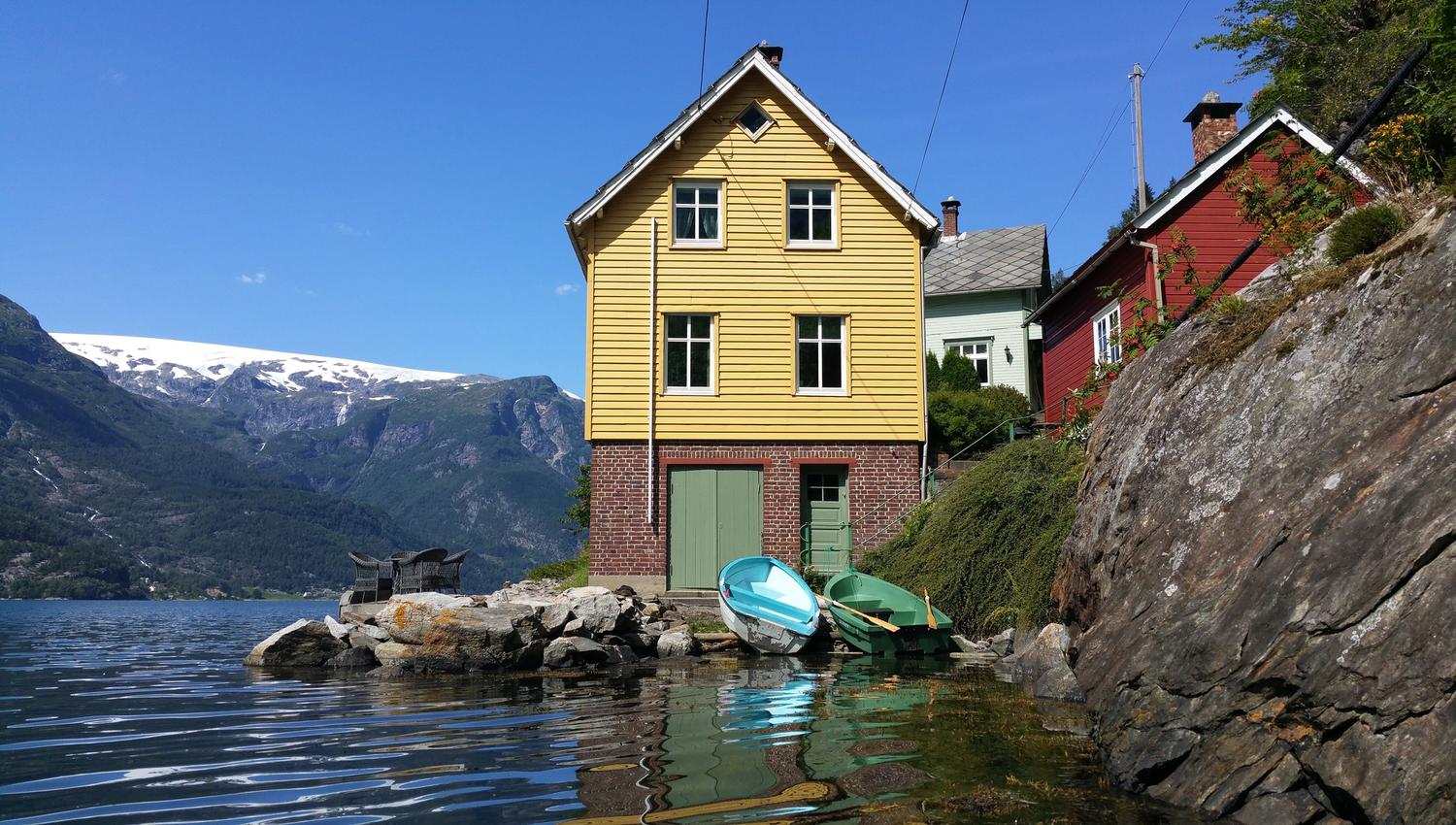 Stana Farm by the Hardangerfjord – charming yellow fjord house with boats and a stunning view of the Folgefonna glacier.