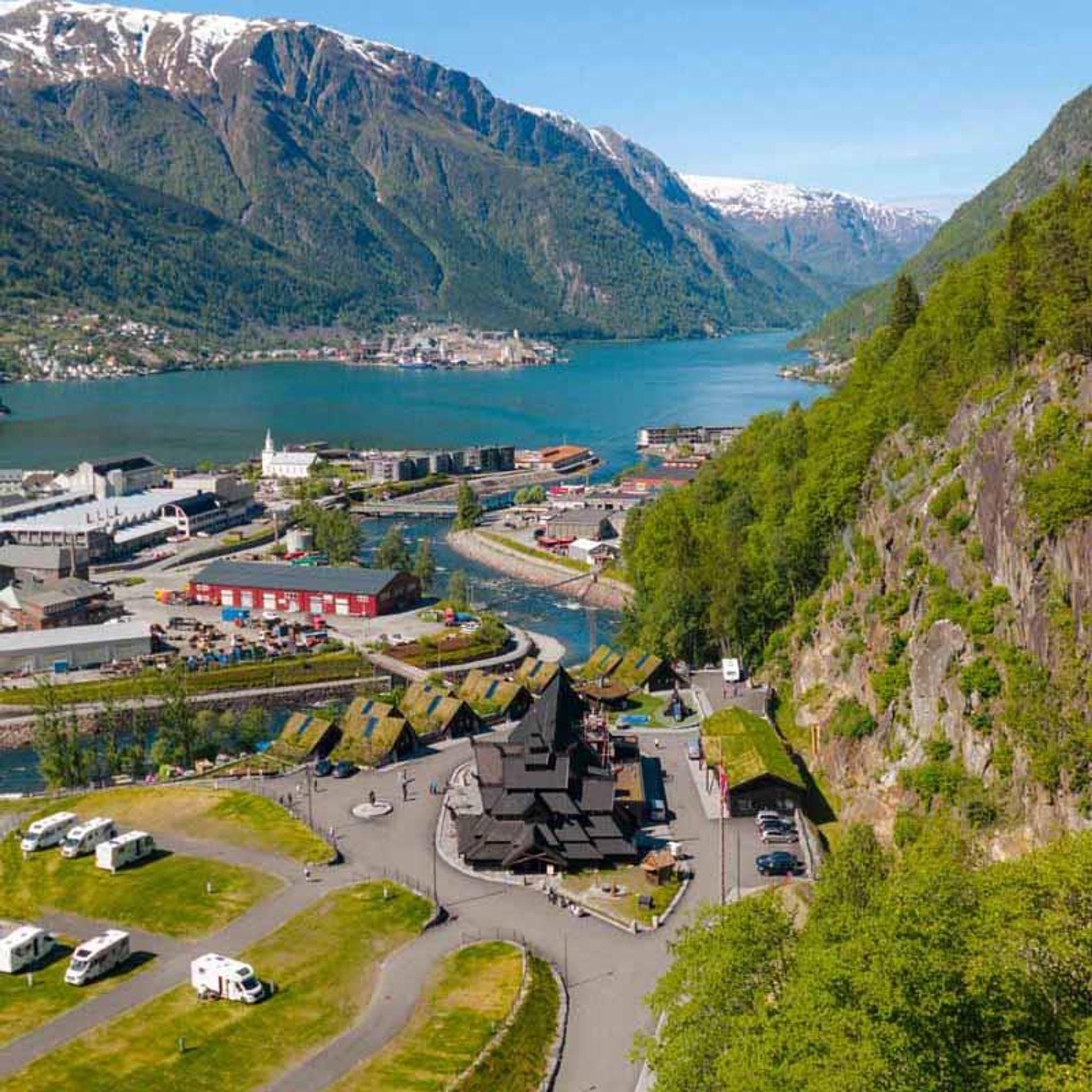 Lothepus Camping i Odda med stavkyrkje, hytter og campingplassar ved Sørfjorden, omgitt av snøkledde fjell i Hardanger