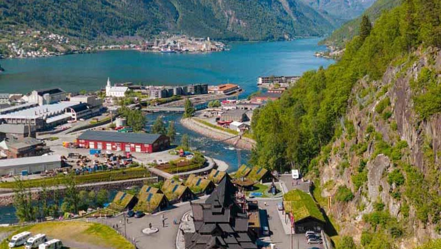 Lothepus Camping i Odda med stavkyrkje, hytter og campingplassar ved Sørfjorden, omgitt av snøkledde fjell i Hardanger