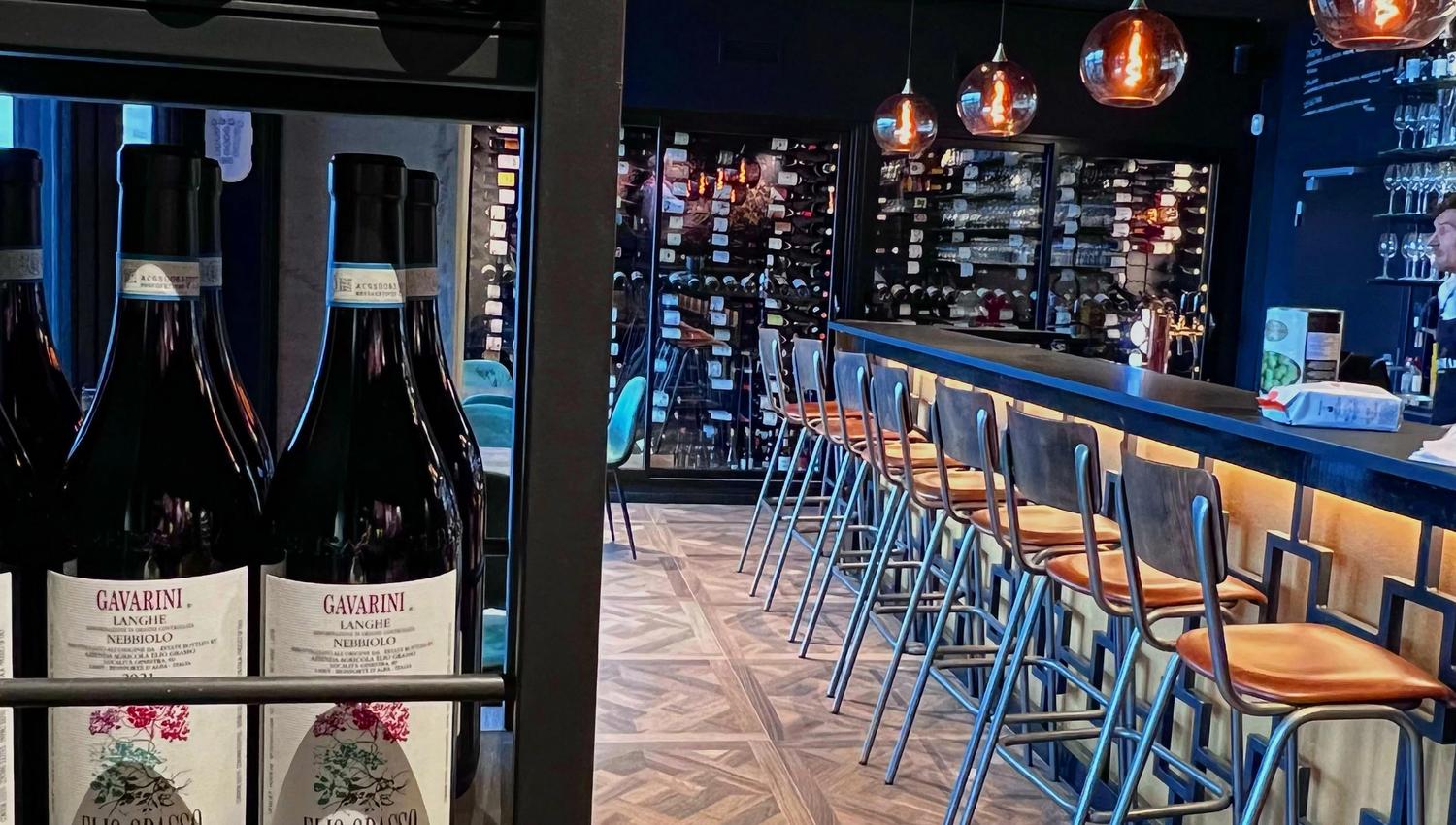 Wine bottles around in the bar on shelves and seatings by the bar