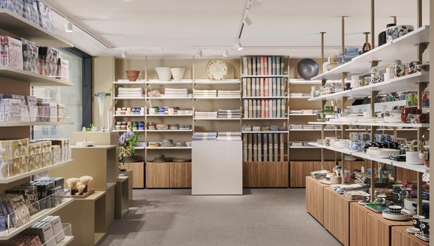 Interiørbilde. Hyller med designvarer. Beige vegger, hvitt tak, grått gulv.
