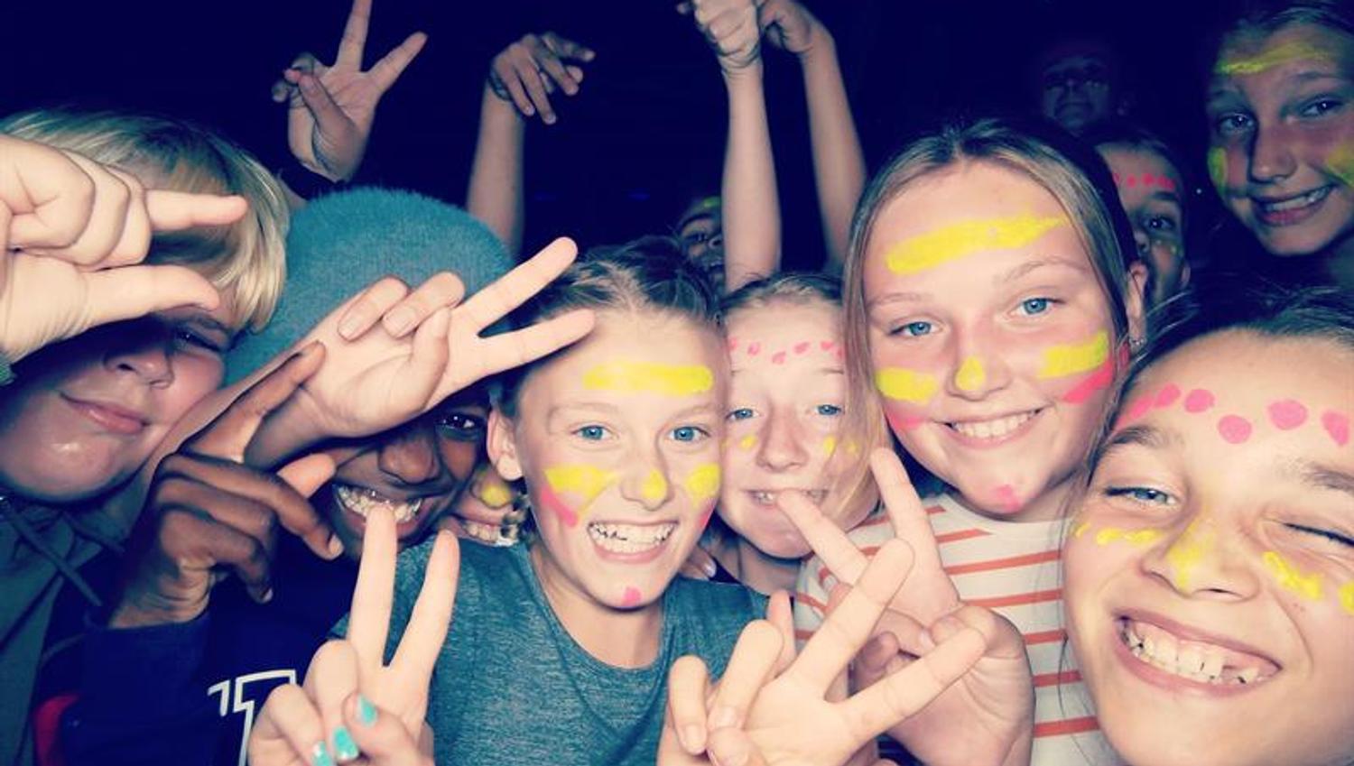 Children with face paint smile at the camera