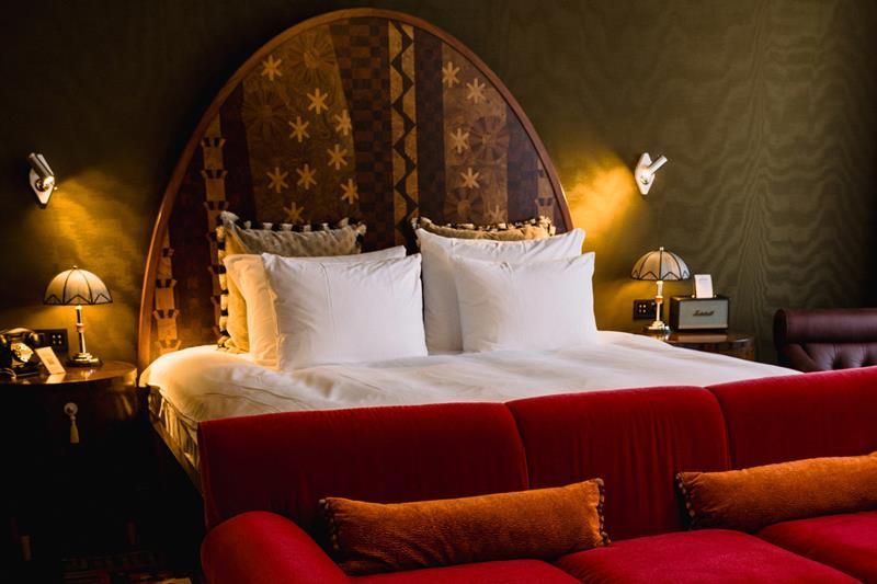 Hotel room with a double bed behind a red sofa