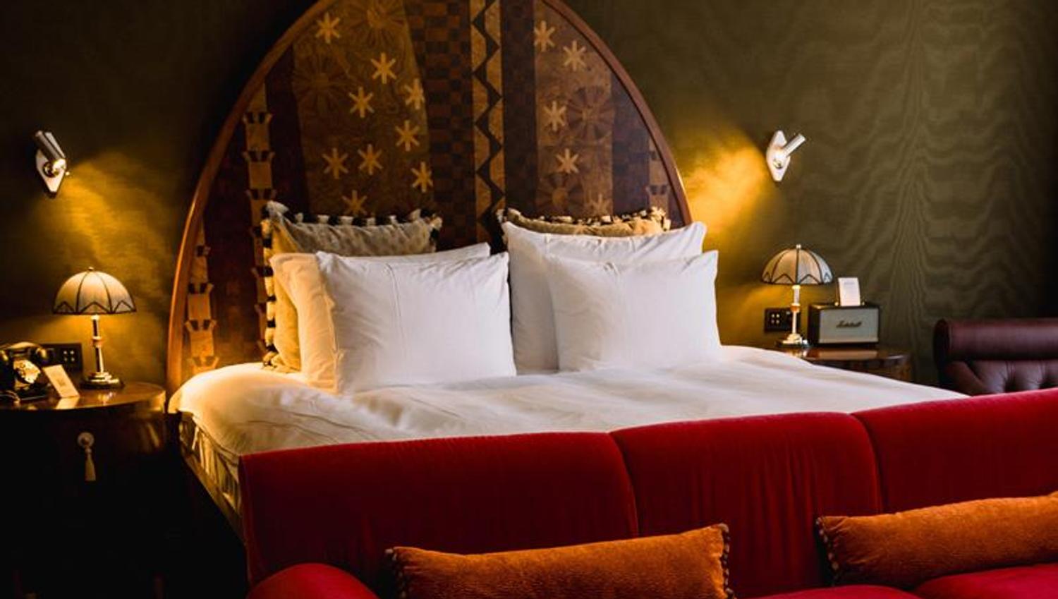 Hotel room with a double bed behind a red sofa