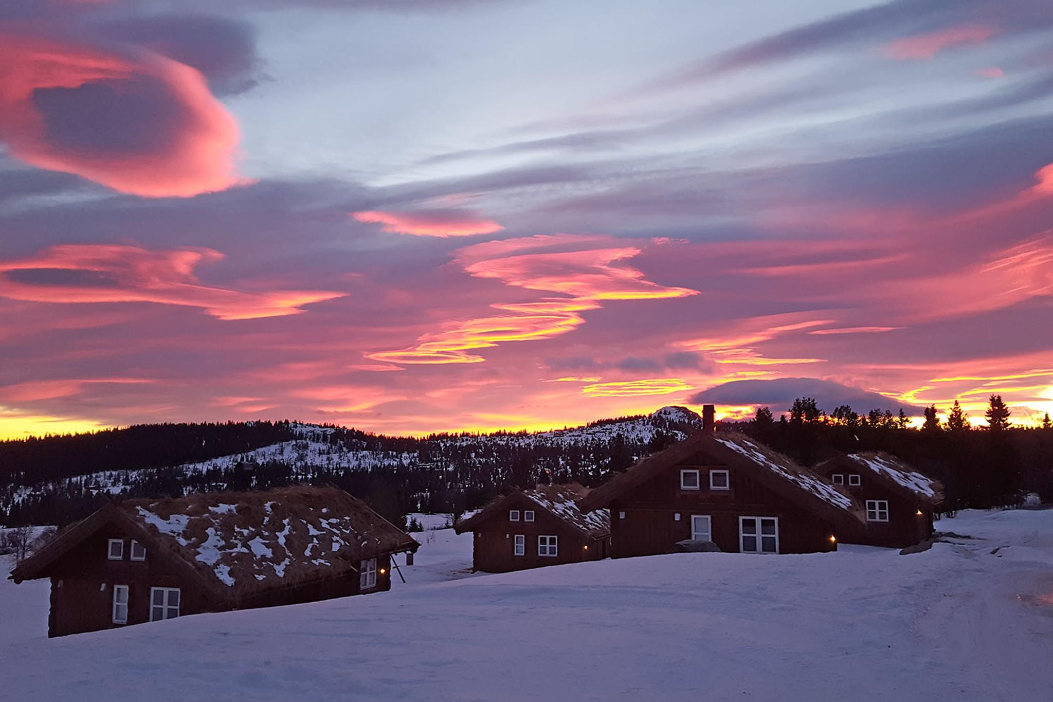 Små trehytter i vinterlandskap i solnedgangen