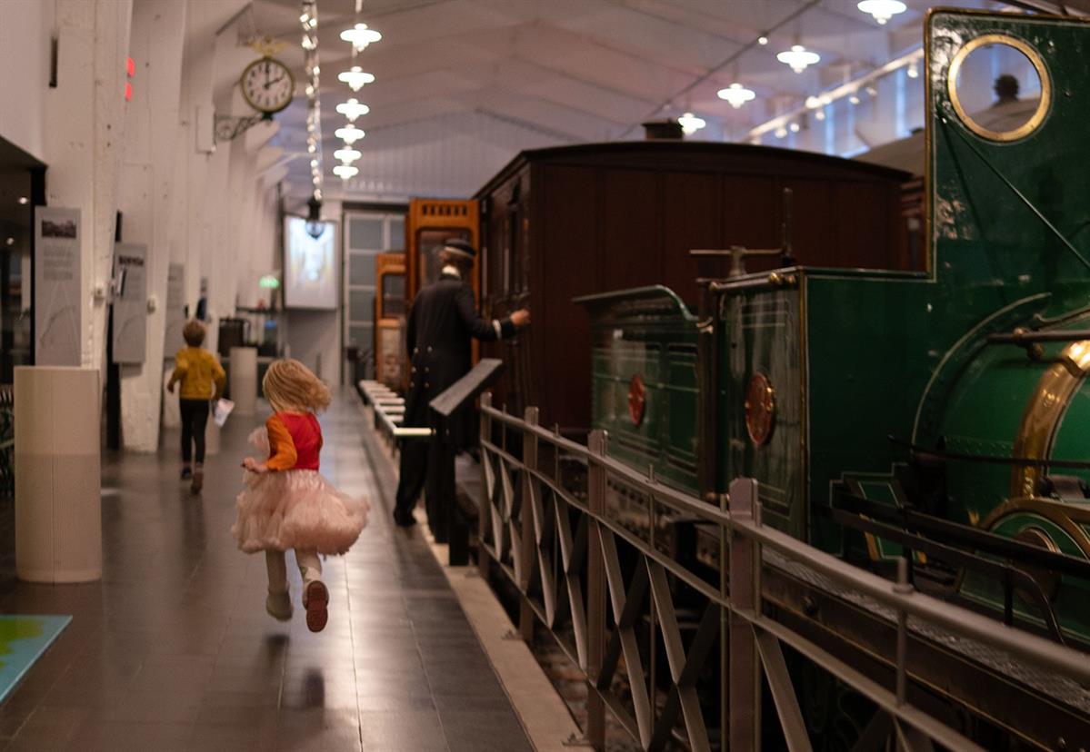 Museum hall with trains and a person walking along the exhibition.