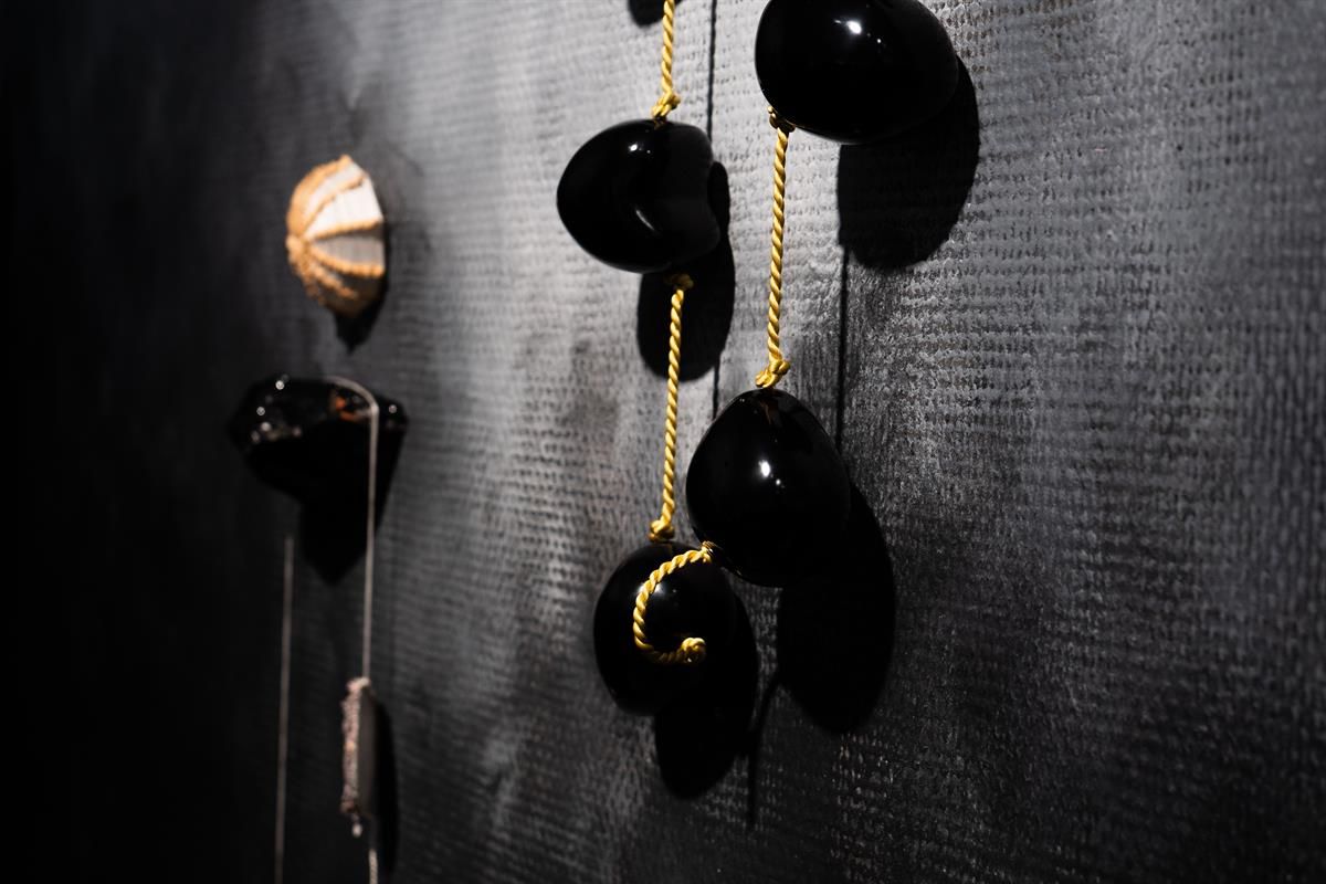 Dark wall installation with hanging glossy organic shapes.
